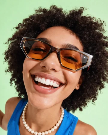 Smiling woman in orange sunglasses against a mint background