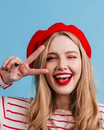 Smiling woman in a red beret making a peace sign