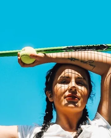 Woman holding a tennis racket above her head in the sun