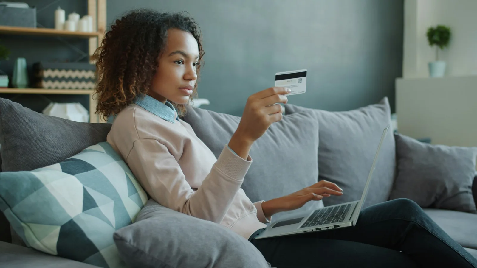 Shopper on a sofa entering her card details on a laptop to finish an online order